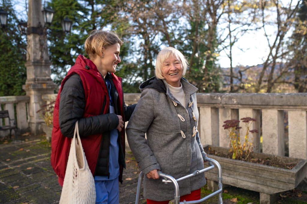 Betreuungskraft begleitet eine ältere Frau mit Rollator bei einem Spaziergang in Herne