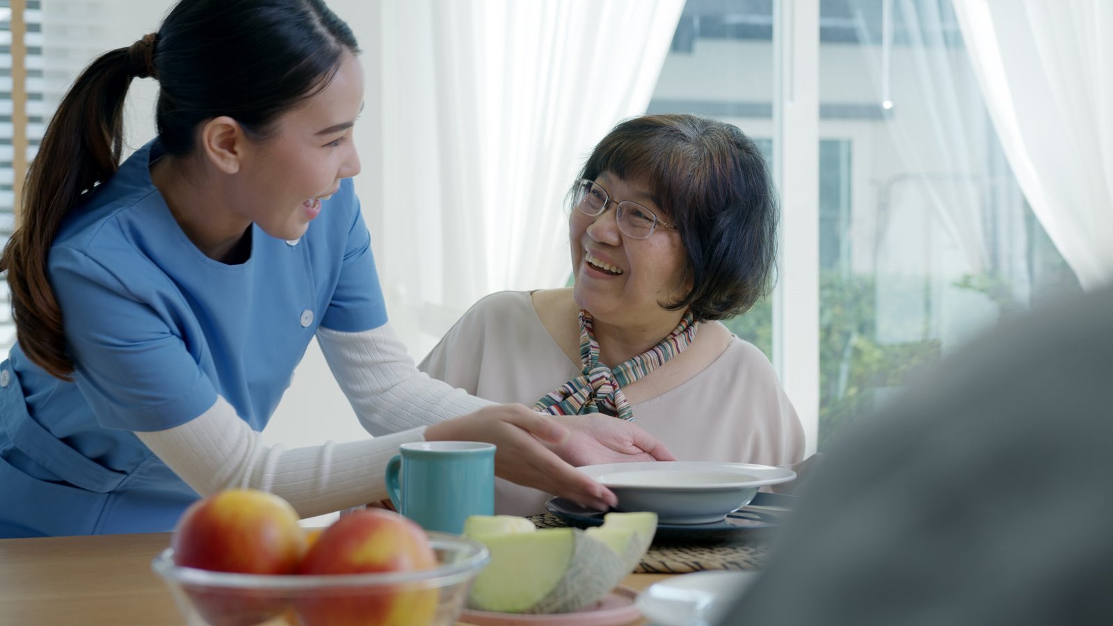 Haushaltshilfe in Herne beim Servieren einer Mahlzeit für eine Seniorin am Esstisch